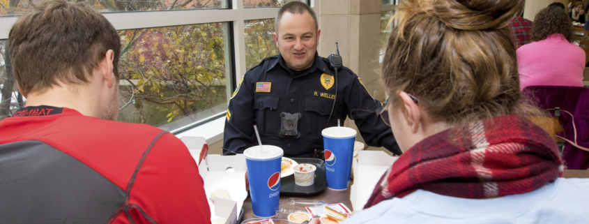 A Ball State University officer is having lunch with a male student and a female student