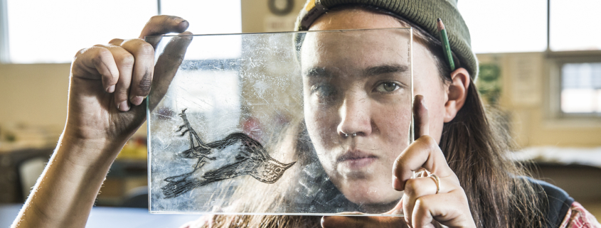 Honors College senior Sarah Fischer holds up a glass etching she made of a dead bird she found.