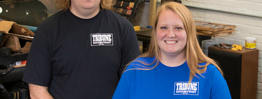 Tribune Showprint owners Kim and Rob Miller, a Ball State alumnus, stand in front of one of the presses inside their Muncie-based shop.