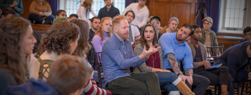 Jesse Tyler Ferguson sits around a crowd of students as he talks