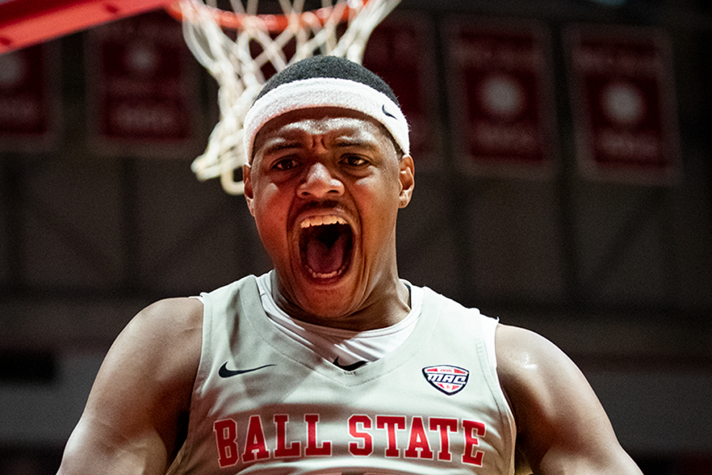 A basketball player makes an emotional face in front of the basketball net