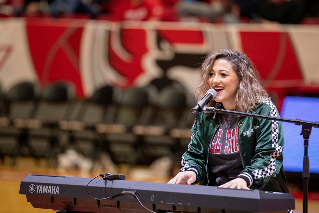 A woman plays a keyboard and sings for fans on the floor of Worthen Arena