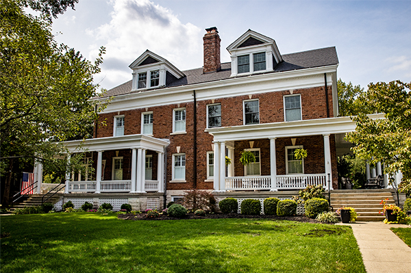 A large brick home with white porch and grassy lawn